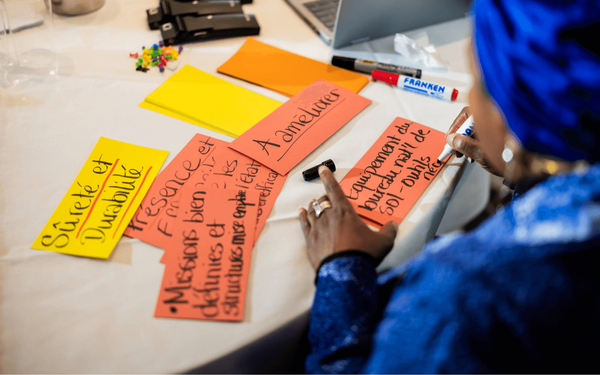 Eine Person beschriftet bunte Karten mit Ideen bei der "Partners for Change"-Konferenz.