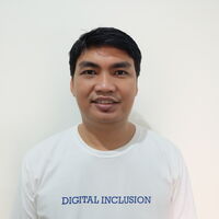 Ein Mann in einem weißen T-Shirt mit der Aufschrift "Digital Inclusion" steht vor einer neutralen, hellen Wand.