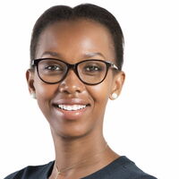 Eine Frau mit Brille und Ohrringen lächelt freundlich in die Kamera vor einem weißen Hintergrund.