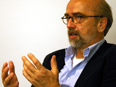 Ein Mann mit Brille und Bart gestikuliert intensiv während eines Gesprächs.