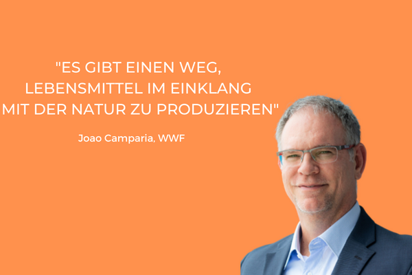 Ein Mann in Anzug steht vor orangefarbenem Hintergrund mit einem Zitat über nachhaltige Lebensmittelproduktion.