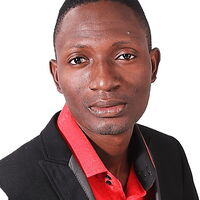 Ein Mann in einem eleganten schwarzen Anzug und rotem Hemd blickt selbstbewusst in die Kamera.