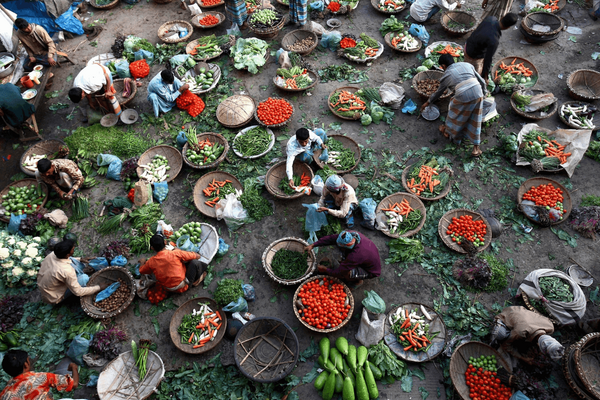 Ein geschäftiger Markt in Bangladesch zeigt Händler, die frisches Gemüse in großen Körben anbieten.