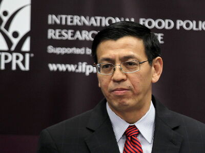 Ein Mann in Anzug und Krawatte steht vor einem Banner des International Food Policy Research Institute.