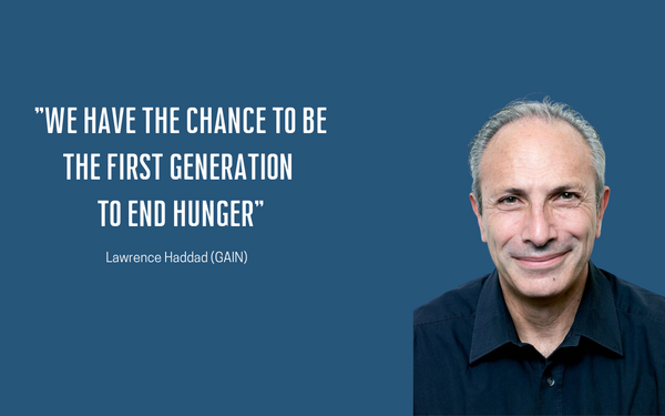 A man smiles beside a motivational quote about ending hunger on a blue background.