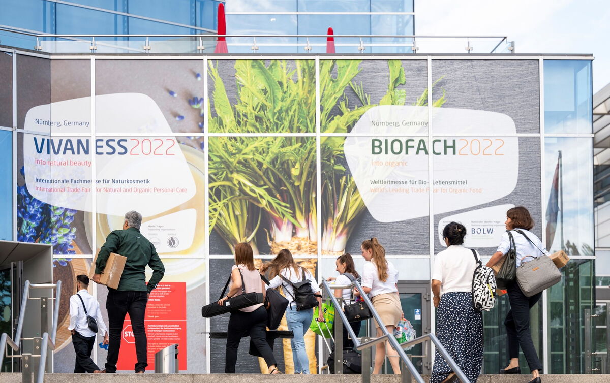 Besucher betreten die NürnbergMesse 2022 für BioFach und Vivaness, vorbei an großen Plakaten der Veranstaltungen.
