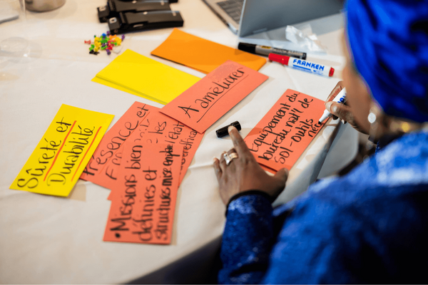 Eine Person beschriftet bunte Karten mit Ideen bei der "Partners for Change"-Konferenz.