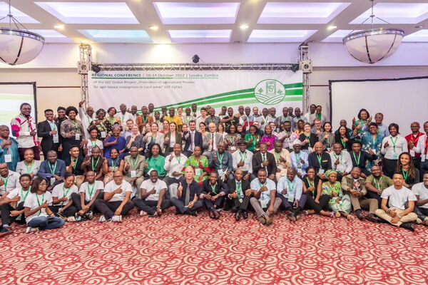 Eine große Gruppe von Menschen posiert lächelnd bei einer Konferenz in Lusaka, 2022, unter einem Banner.