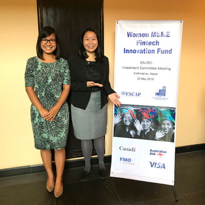 Zwei Frauen stehen lächelnd neben einem Plakat für den Women MSNE Fintech Innovation Fund in Kathmandu.