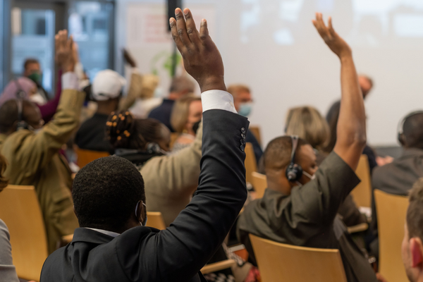Teilnehmer einer Konferenz heben die Hand, um sich an einer Diskussion über die Gestaltung von Lebensmittelsystemen zu beteiligen.