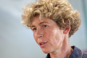 A person with curly hair is speaking passionately in a close-up shot.