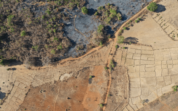Luftaufnahme von Madagaskars Landschaft zeigt Felder, Pfade und verbrannte Vegetation, die Entwicklung und Wandel verdeutlichen.