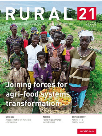 Eine Gruppe von Menschen steht auf einem Feld mit geernteten Früchten, die ländliche Zusammenarbeit symbolisierend.