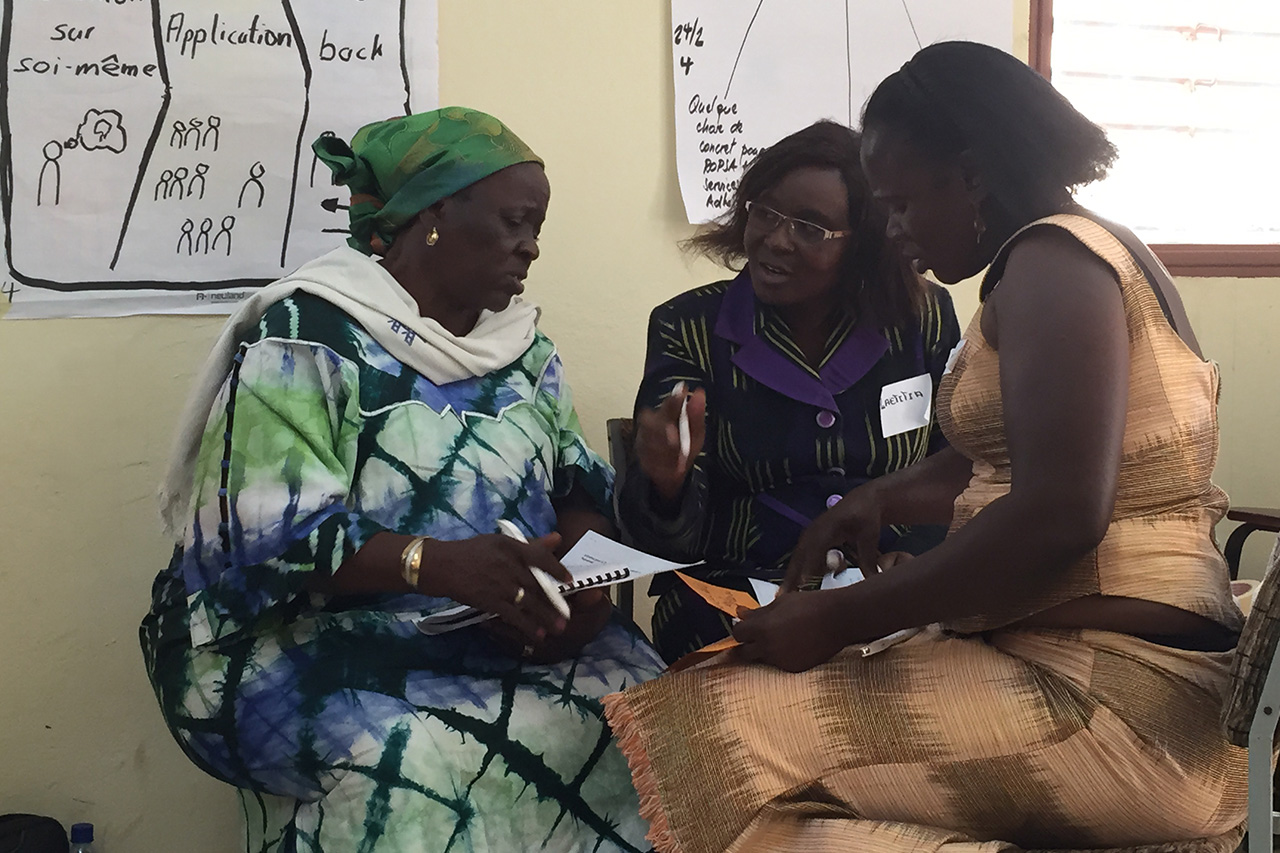 Drei Frauen diskutieren intensiv miteinander, während sie Notizen in einem Workshop machen.